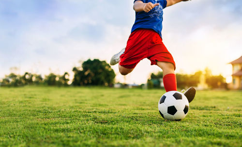Low angle view of boy playing soccer on field