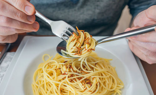 Midsection of man having noodles and worms in restaurant