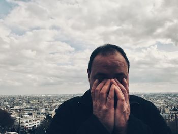 Close-up of sad man standing against cityscape