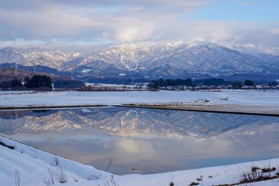 Scenic view of lake by snowcapped mountains against sky