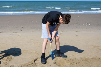 High angle view of boy playing with sand at beach