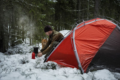 Man in winter forest in front of tent