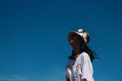 Low angle view of woman against blue sky