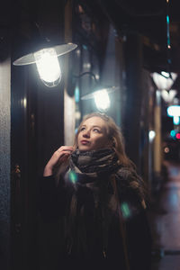 Young beautiful woman in glasses on a city street at night in the light of lanterns