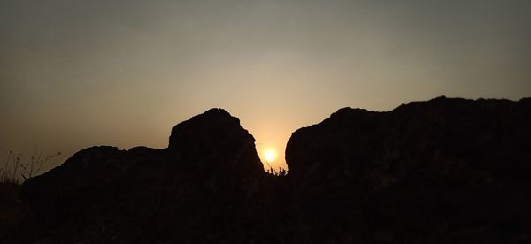 Silhouette rock formations against sky during sunset