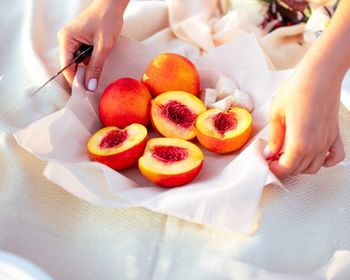 Woman's hands holding peach placed on a serviette