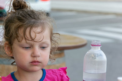 Close-up of cute girl looking at water bottle