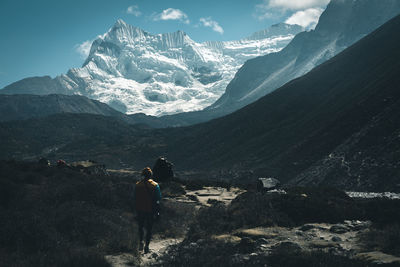 Rear view of man walking against snowcapped mountains