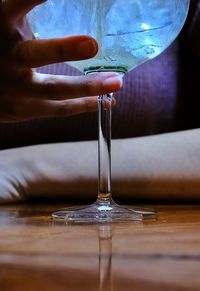 Close-up of hand pouring wine in glass on table