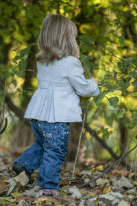 Rear view of girl standing against tree