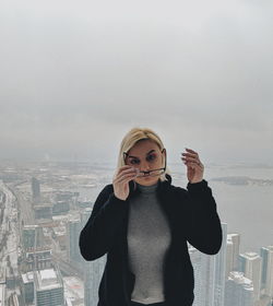 Portrait of young woman using smart phone against sky