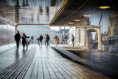 People walking under bridge by building