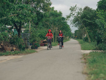 Rear view of people riding bicycle on road