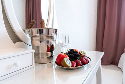 Romantic in hotel room, bottle of champagne, ice bucket, glasses and fruits.