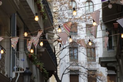 Low angle view of light bulbs with streamers hanging in front of house