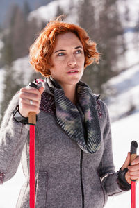 Woman holding ski poles while standing outdoors