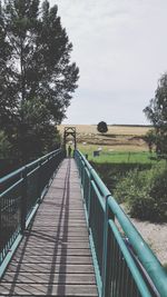 Footbridge leading to bridge against sky