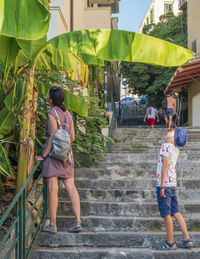 Mom and son are looking at a banana tree in the street.