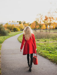 Rear view of woman walking on red umbrella