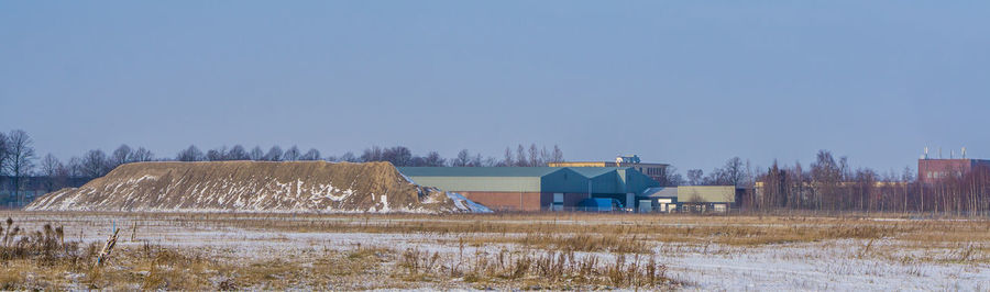 Barn on field against clear sky during winter