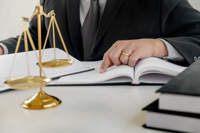 Midsection of man reading book on table