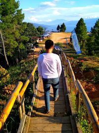 Full length rear view of man standing on footbridge