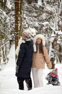 Portrait of smiling woman standing on snow covered field