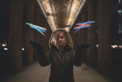 Woman throwing colorful toy while standing under bridge