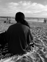 Rear view of man sitting on beach