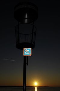 Illuminated information sign at sea against sky at night