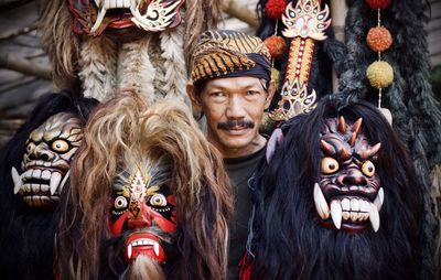 Portrait of man holding mask for sale at market stall