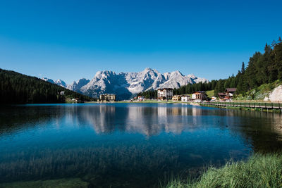 Scenic view of lake and mountains against clear blue sky