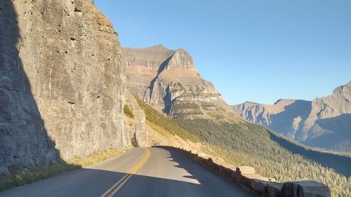 Winding mountaintop road with the valley below and blue skies ahead 