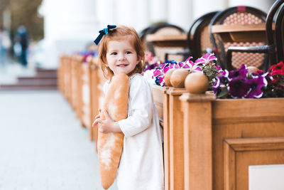 Portrait of cute girl holding loaf of bread