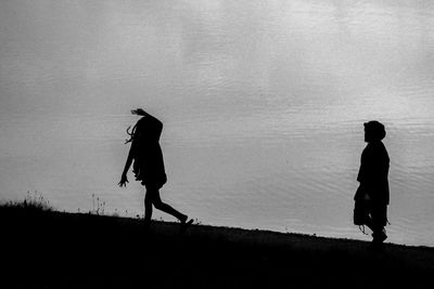 Silhouette man walking on water against sky