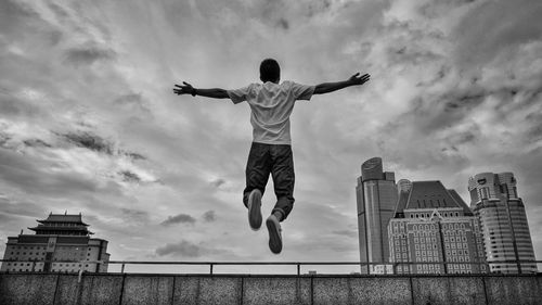 Low angle view of man jumping against sky