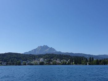 Scenic view of sea and mountains against clear blue sky