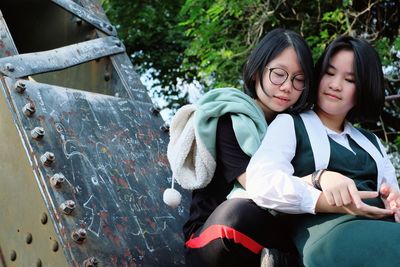 Friends sitting against metallic structure