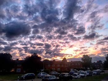 Cars on city against sky during sunset