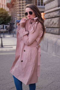 Woman with pink umbrella standing on street