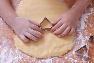 Cropped image of hands making heart shape cookies during christmas