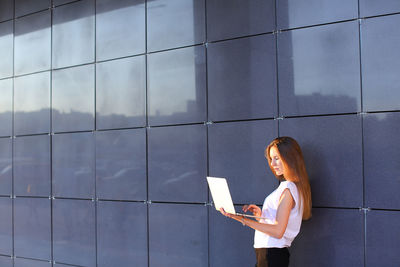 Rear view of woman standing against wall