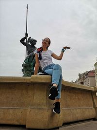 Low angle view of woman sitting against sky