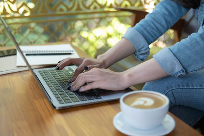 Midsection of woman holding coffee cup on table