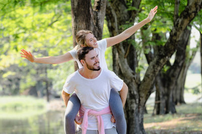 Young couple kissing against trees