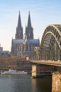 Bridge over river by building against sky