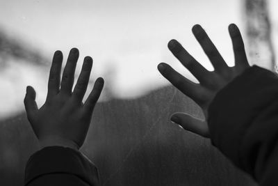 Cropped hands of children touching window