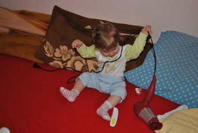 Boy playing with hair dryer on bed at home