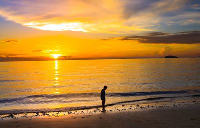 Silhouette people on beach against sky during sunset