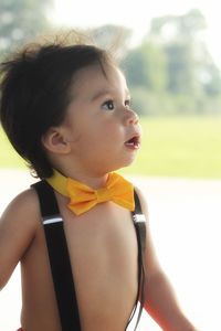 Close-up of shirtless baby boy wearing suspenders and bow tie